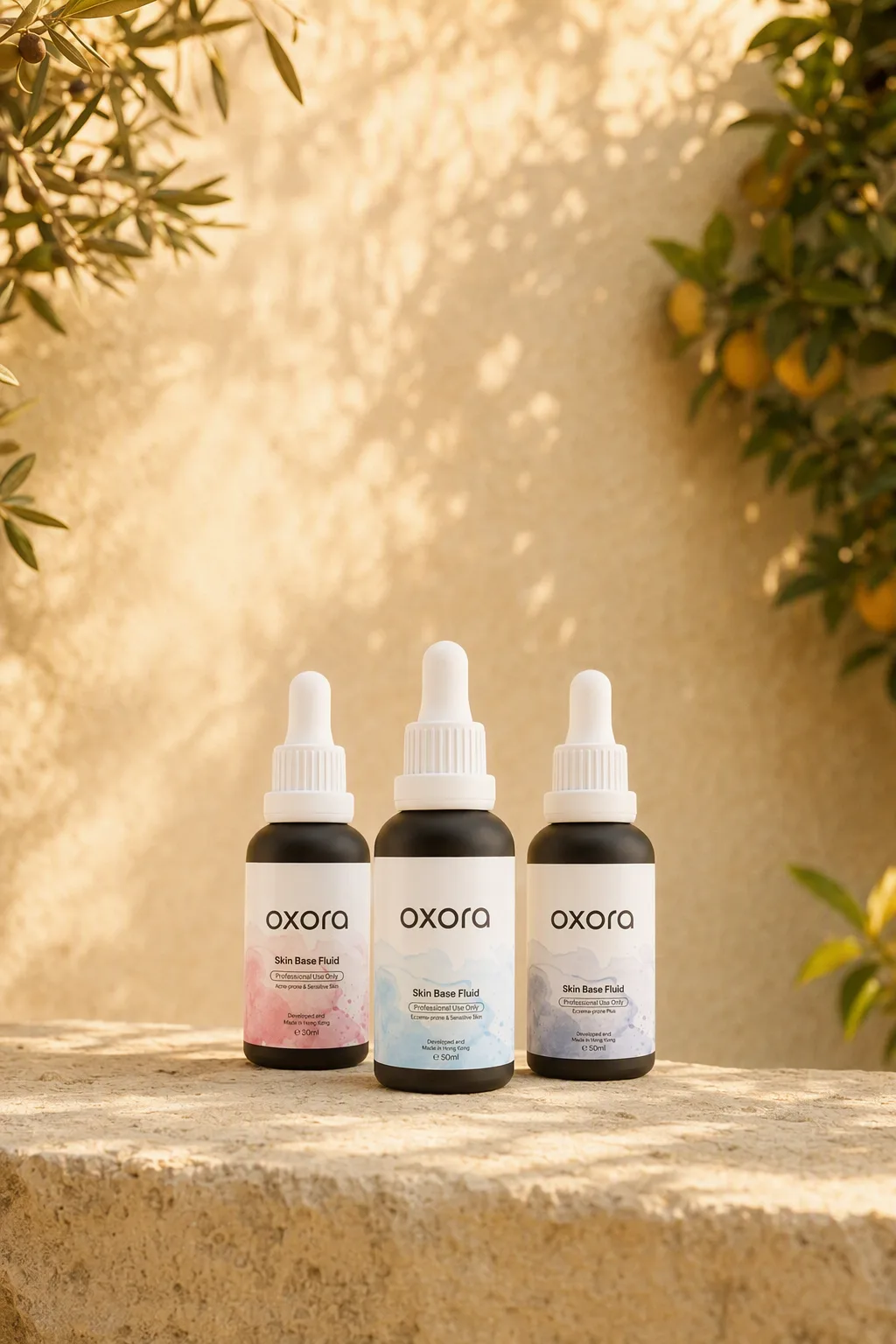 Oxora Acne-prone, Eczema-prone and Eczema-prone Plus Skin Base Fluid in 30 ml and 50 ml glass dropper bottles, on a sunlit limestone ledge in a garden